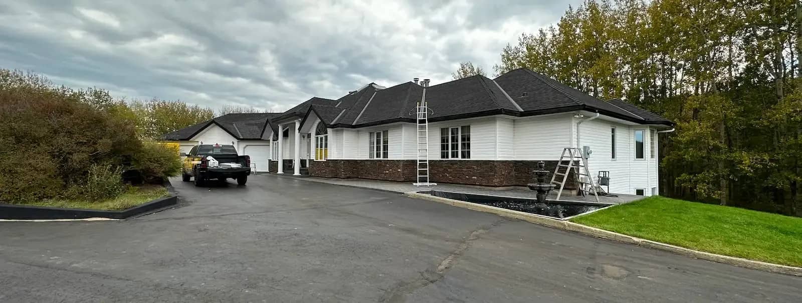 Bungalow with a new black shingle roof under a cloudy sky