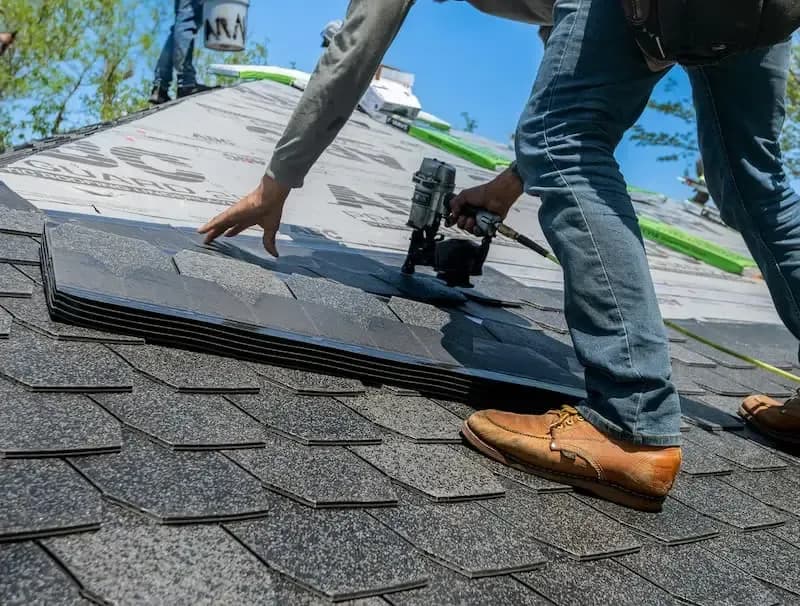 Roofer nailing down asphalt shingles